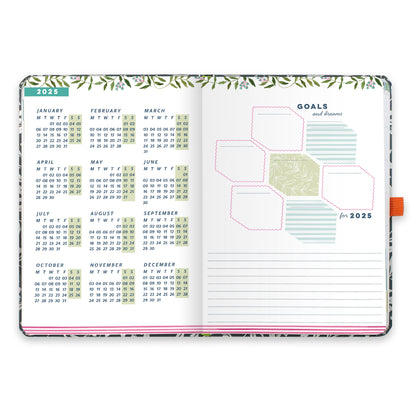 An open diary planner with a goals and dreams for the year page and a page with year micro calendars for 2025.