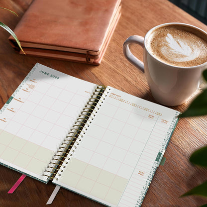 Open Family Life Book diary on a wooden table next to a cappuccino.