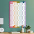 Academic wall planner with rainbow design hung above a wooden table